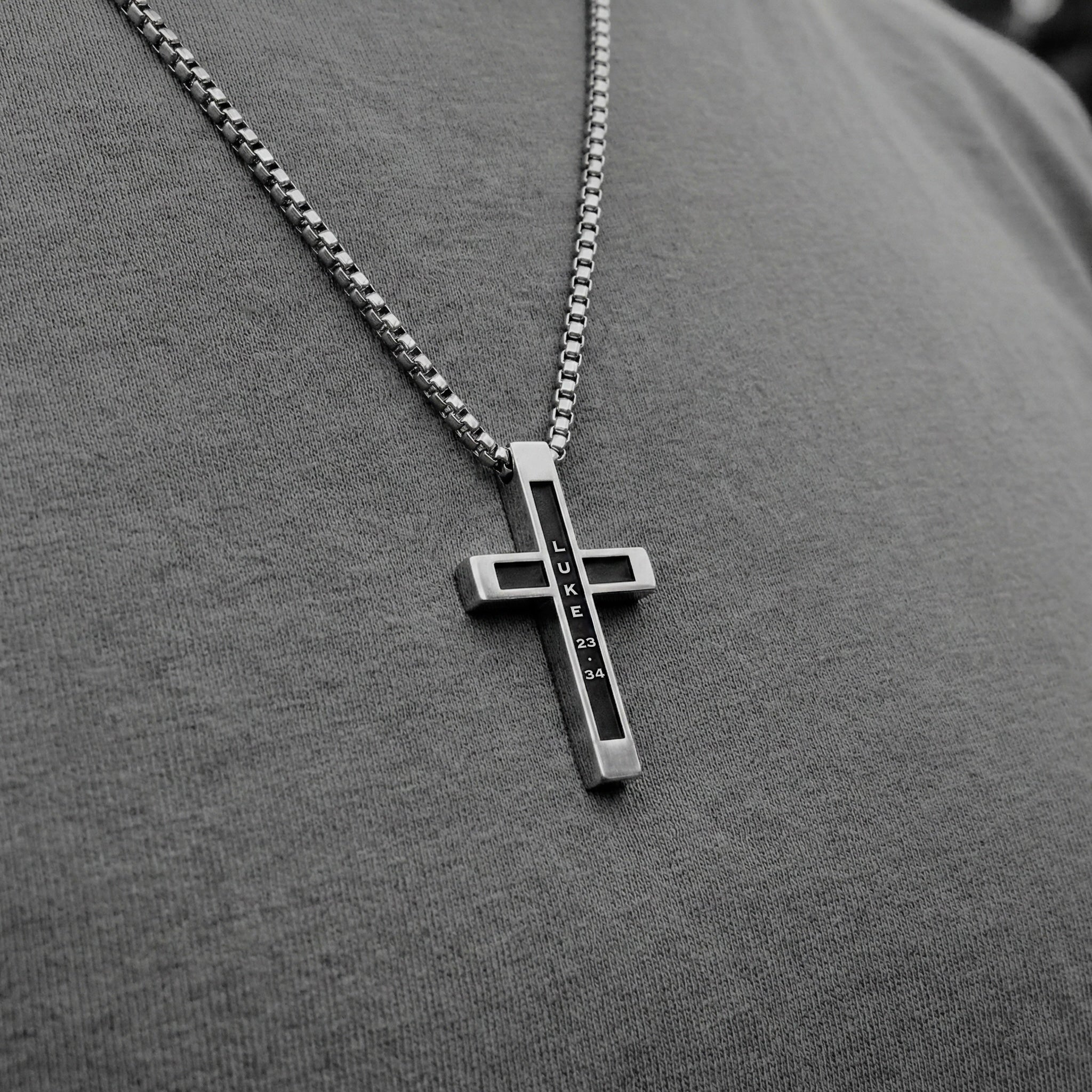 Luke 23:34 | Close-up of man wearing stainless steel cross necklace with Bible verse